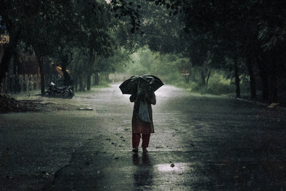 woman in red dress holding umbrella walking on the street