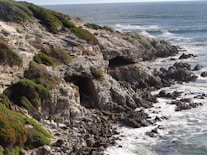 brown rocky mountain beside sea during daytime