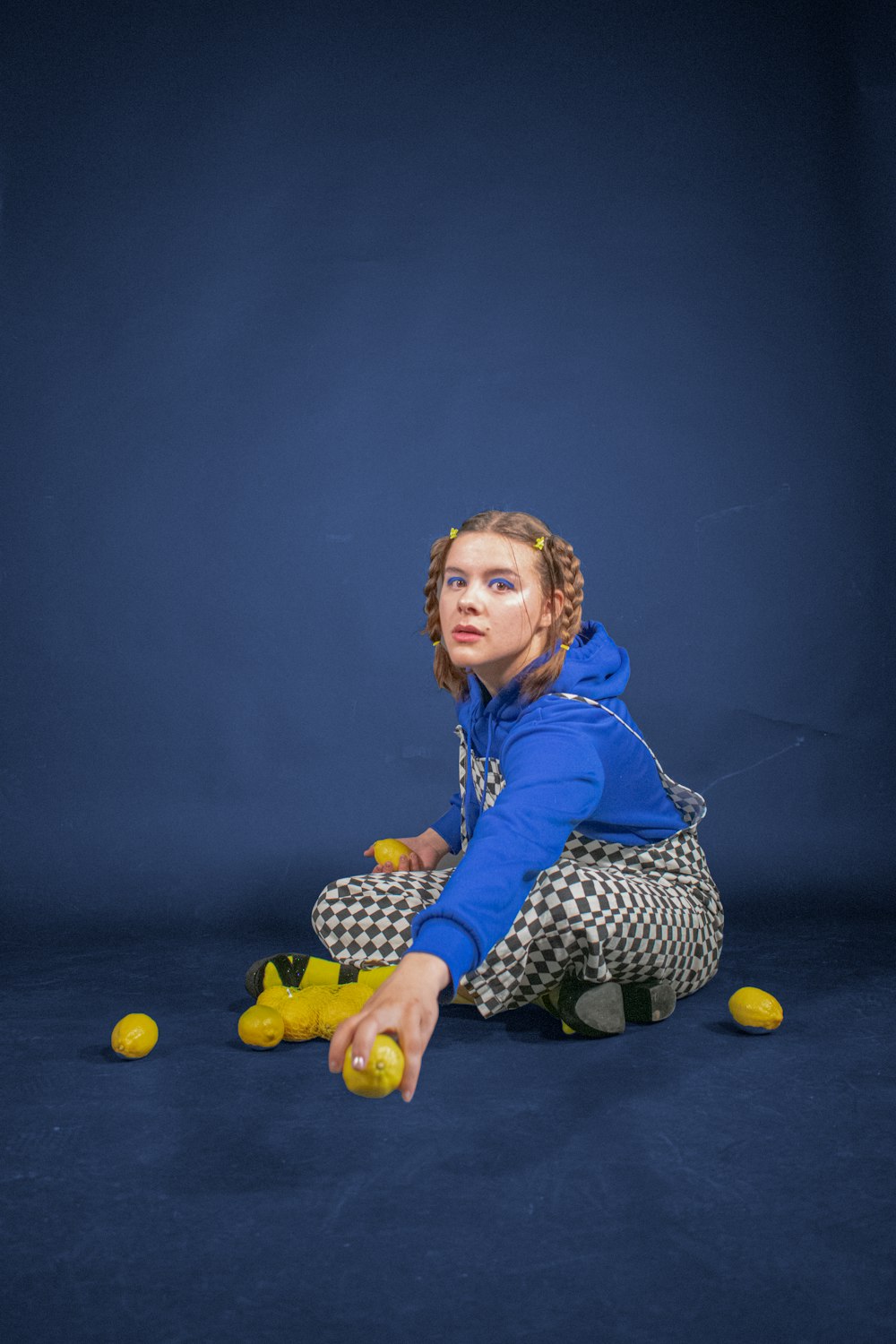 girl in blue hoodie and black and white polka dots pants sitting on floor
