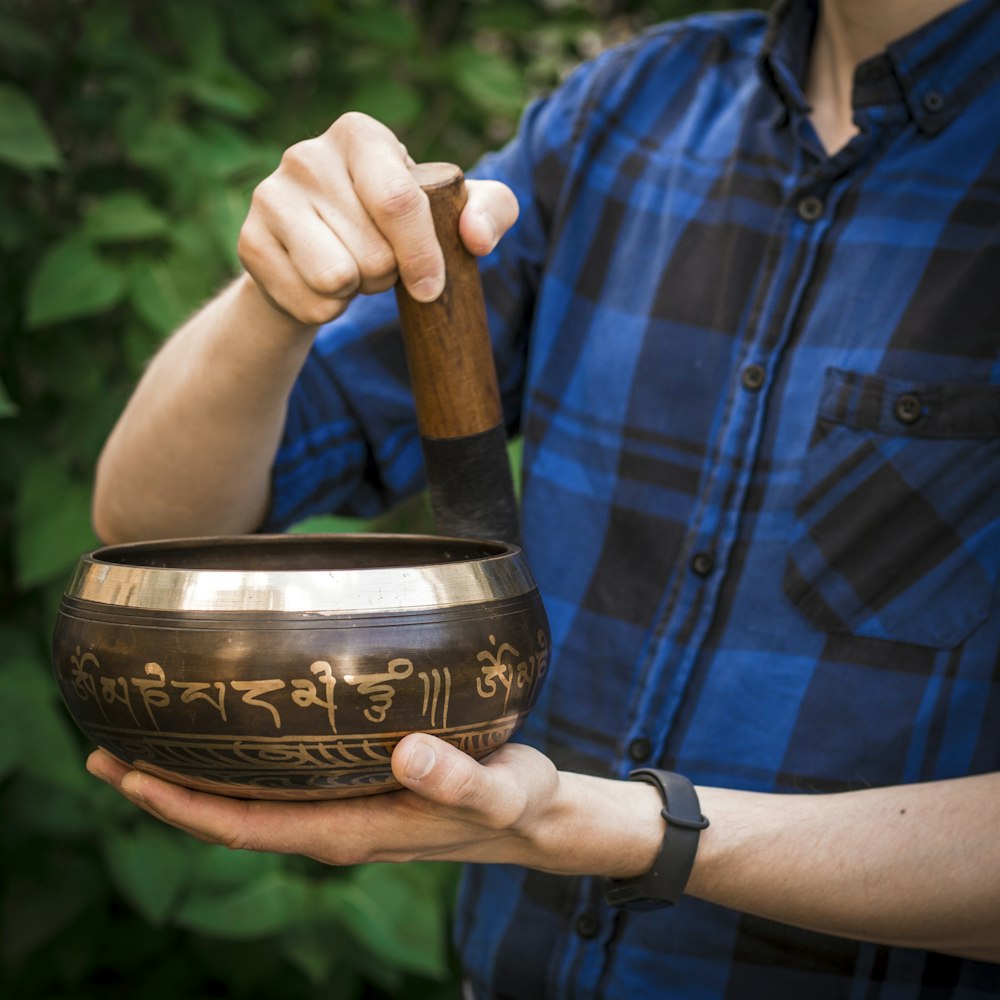 person in blue and black plaid button up shirt holding brown wooden mortar and pestle