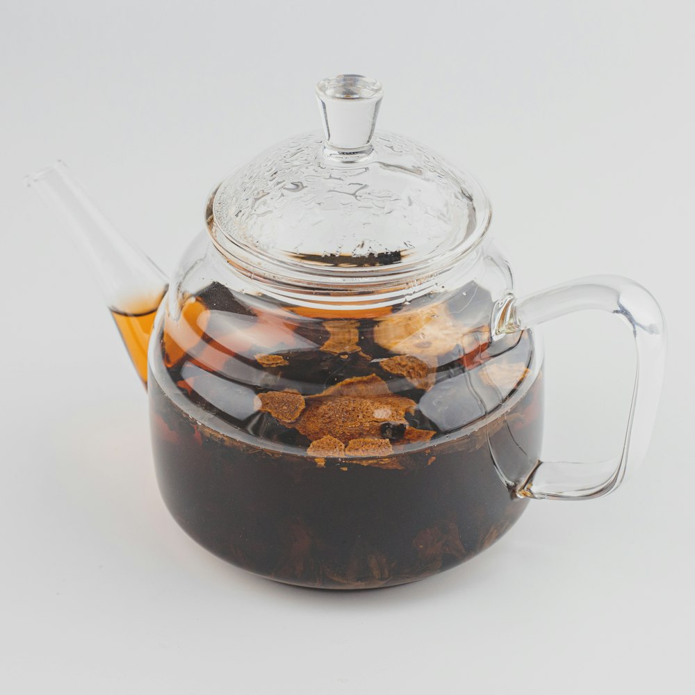 clear glass teapot with brown liquid