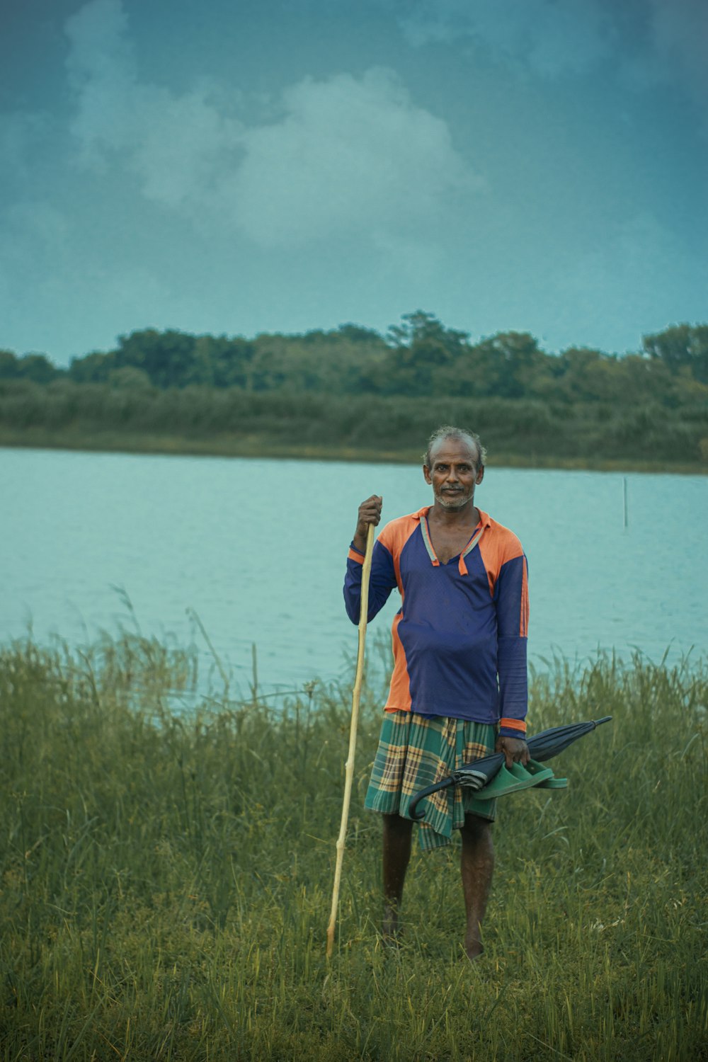 woman in blue and red vest holding boat paddle standing on green grass field during daytime