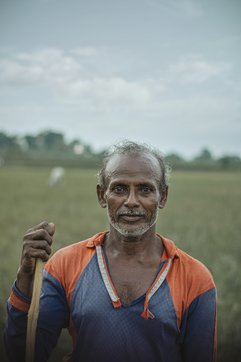 man in blue and orange v neck shirt standing on green grass field during daytime