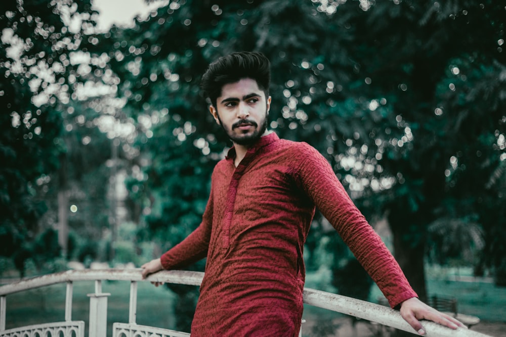 woman in red sweater standing near white fence during daytime