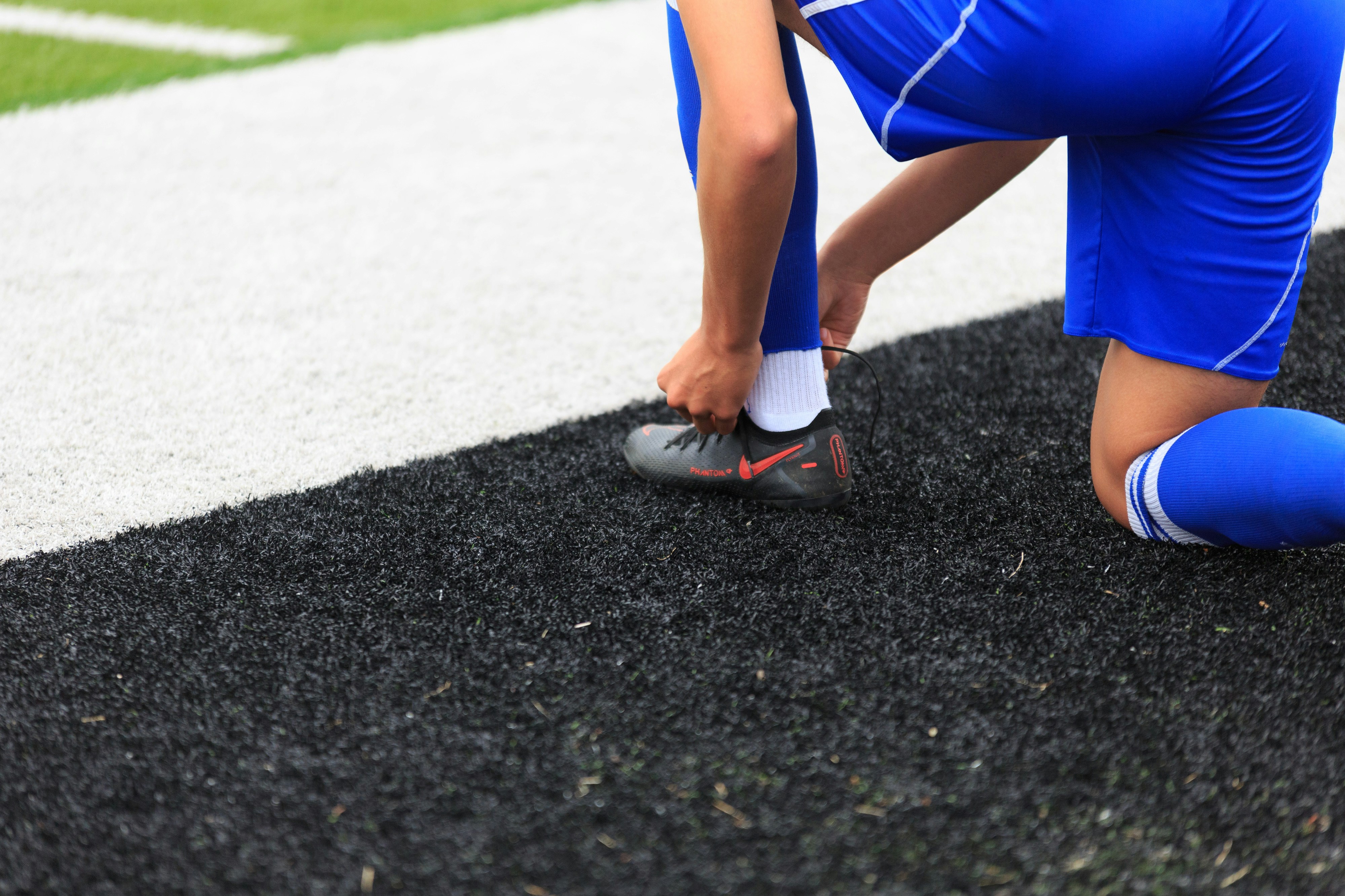 A soccer play takes a moment to tie his shoes.