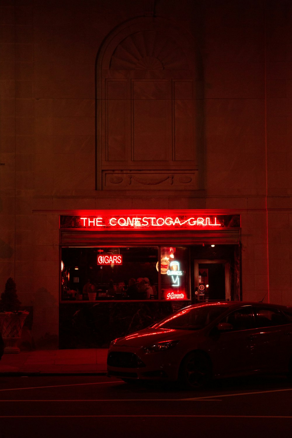 red car parked in front of store during night time