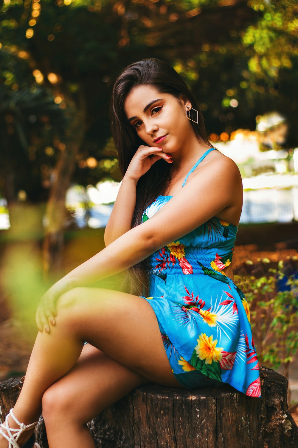 woman in blue and yellow floral spaghetti strap dress sitting on ground