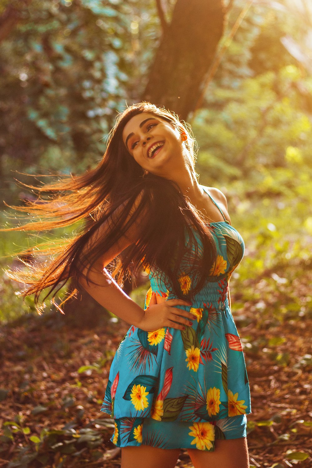 woman in blue and yellow floral dress standing on brown dried leaves during daytime