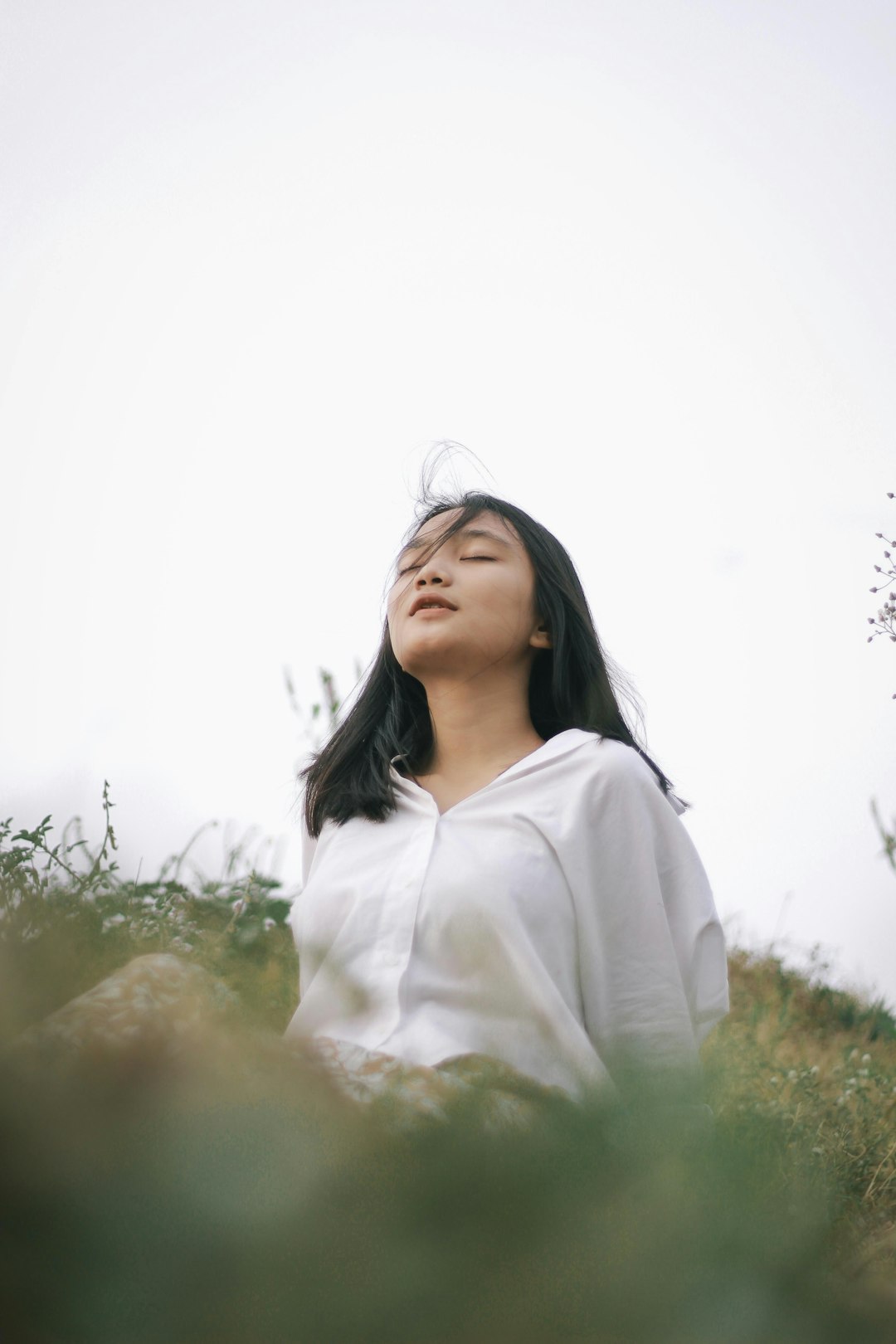 woman in white long sleeve shirt standing on green grass field during daytime