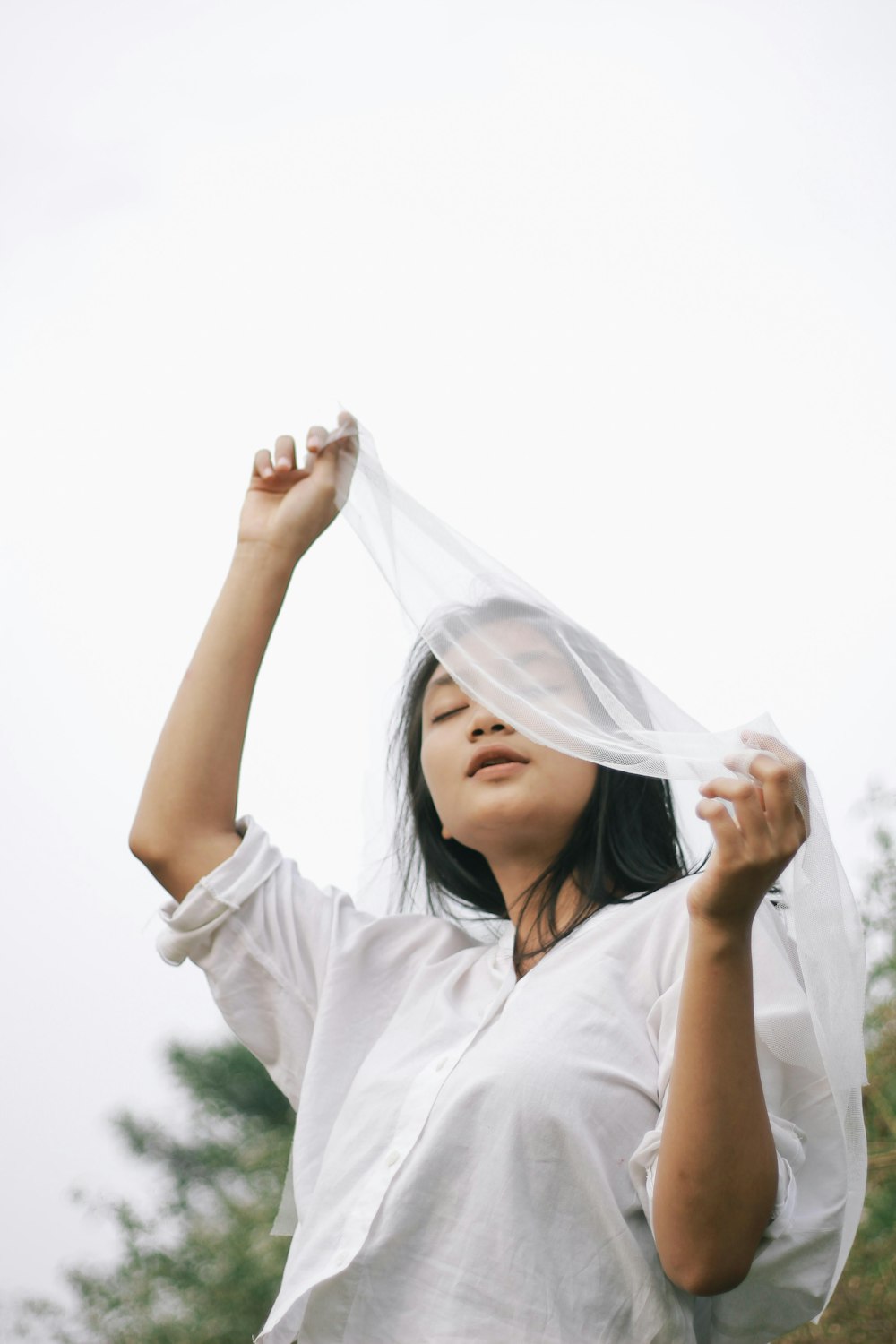 woman in white hijab covering her face with white sheer textile