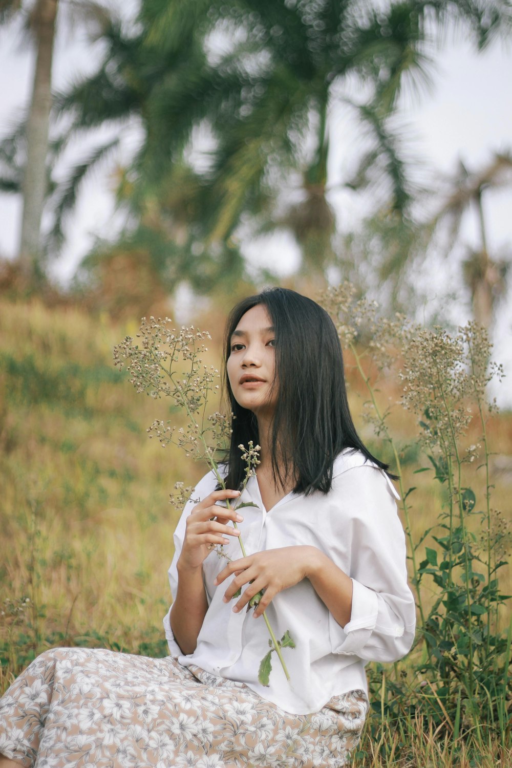 woman in white long sleeve shirt standing on brown grass field during daytime