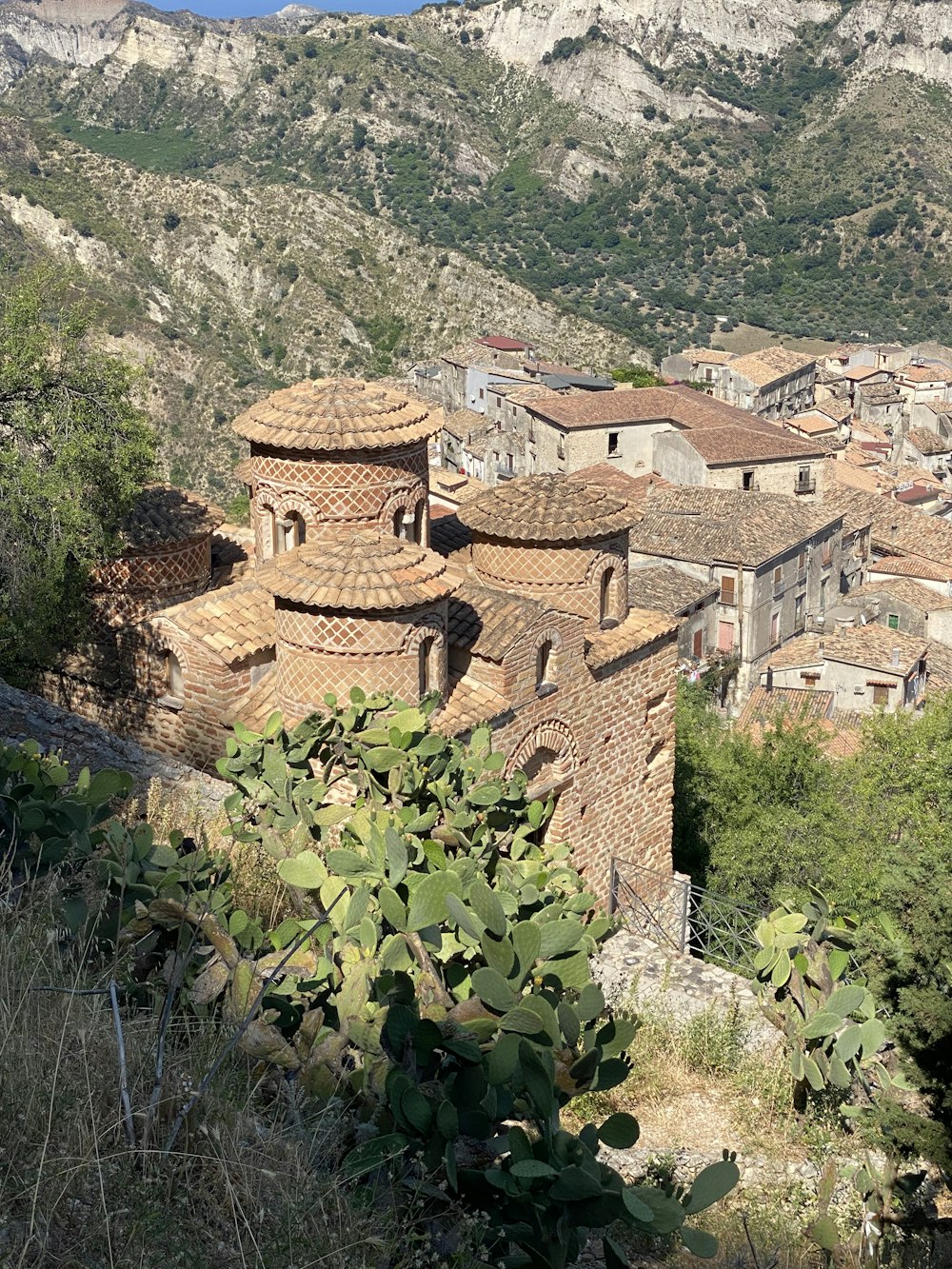 brown brick building near green trees and mountain during daytime