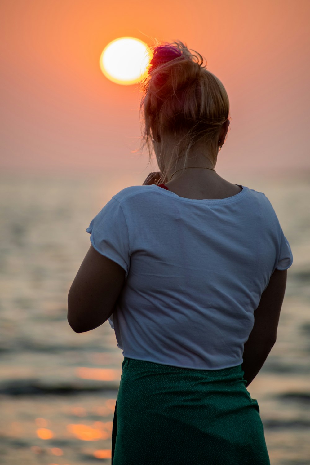 woman in white crew neck t-shirt and green shorts standing near body of water during