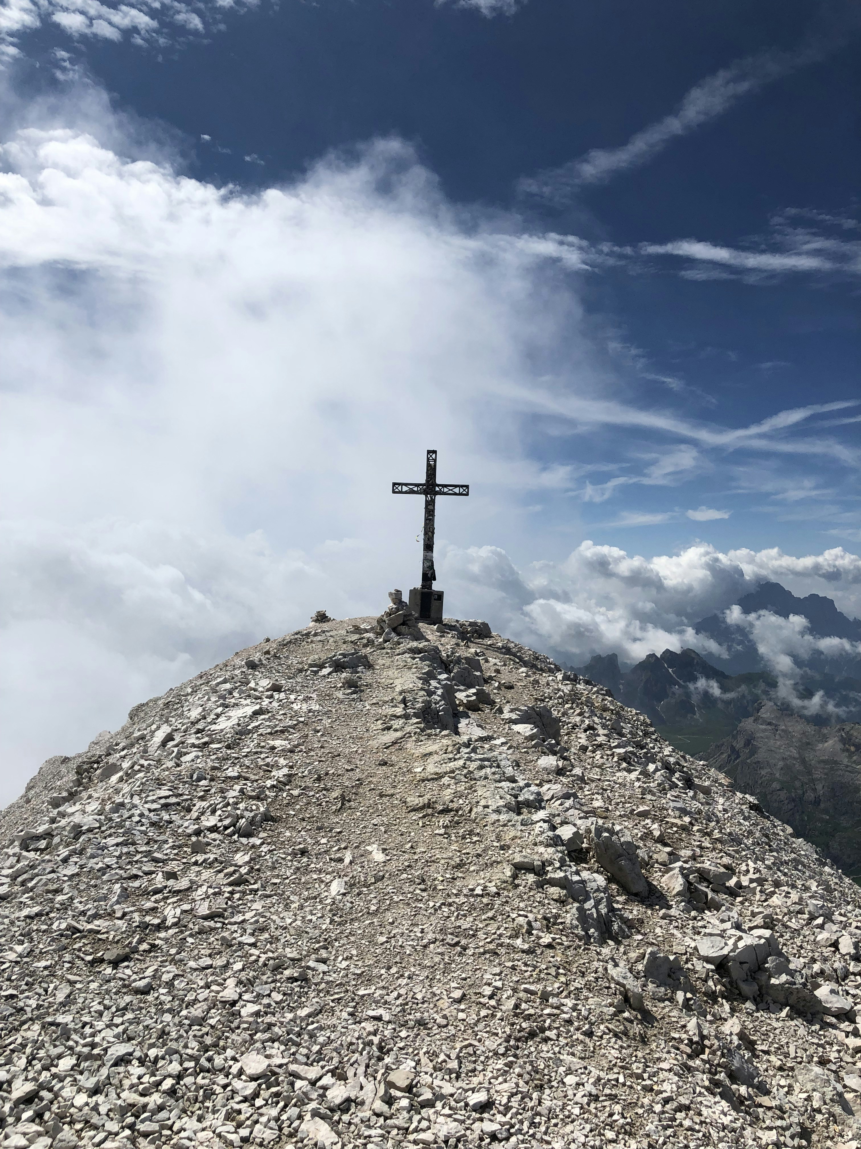 cross on top of mountain under blue sky during daytime