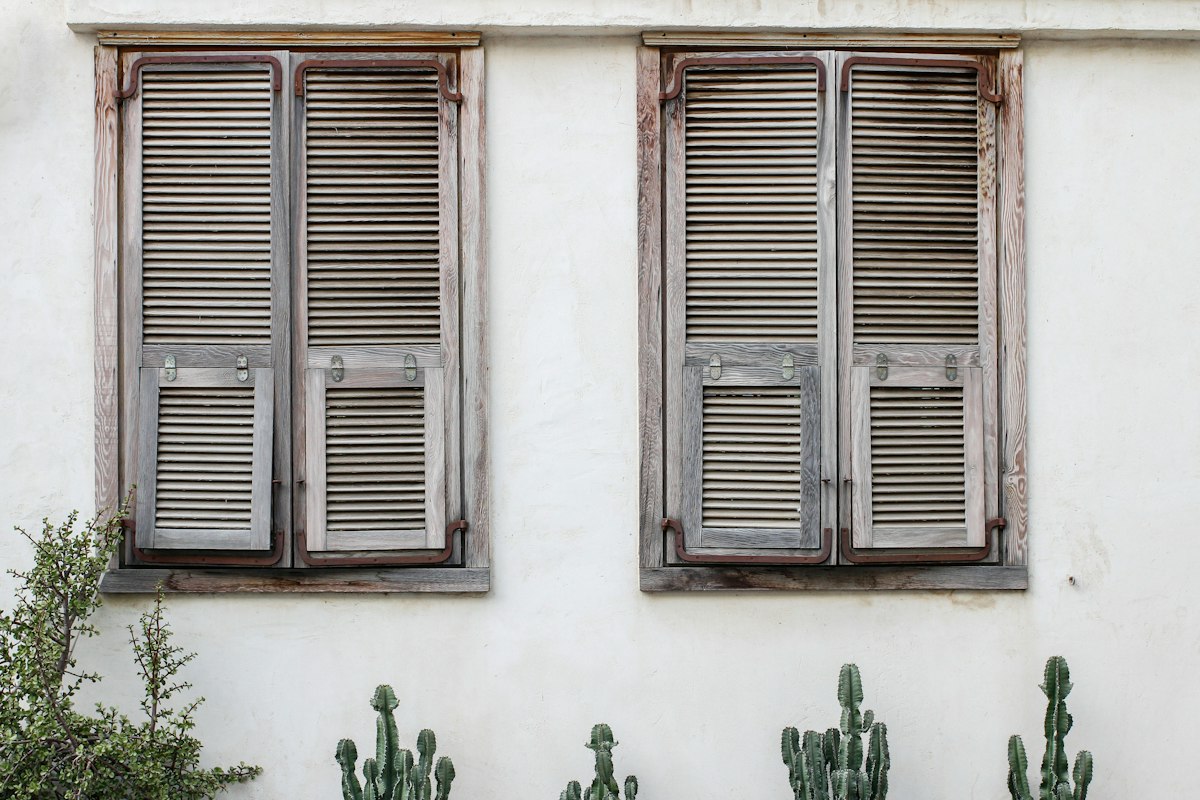 Shuttered windows on a white stucco exterior wall