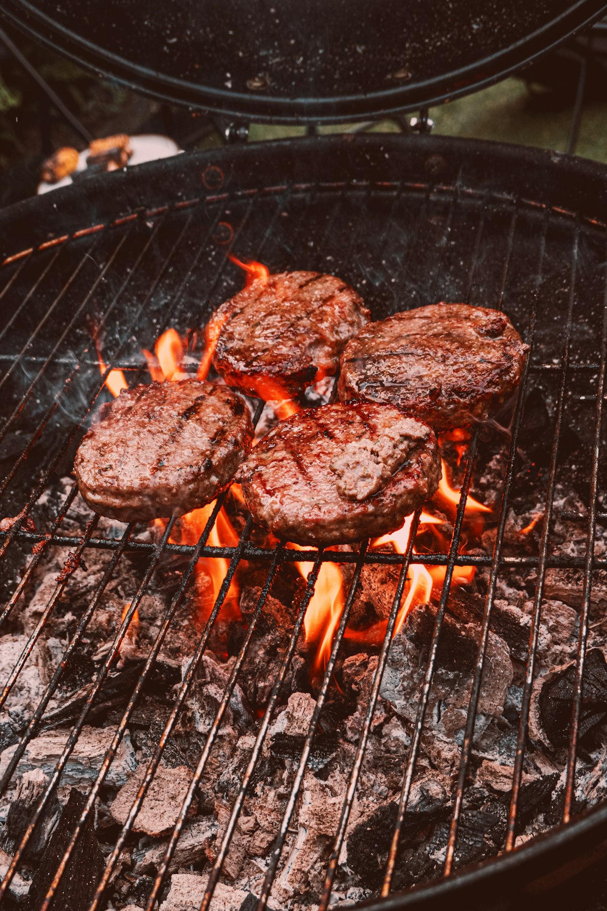 Burgers and steaks sizzling on a black charcoal grill &mdash; exactly the kind of cookout Aldi's Grill Master Collection is built for