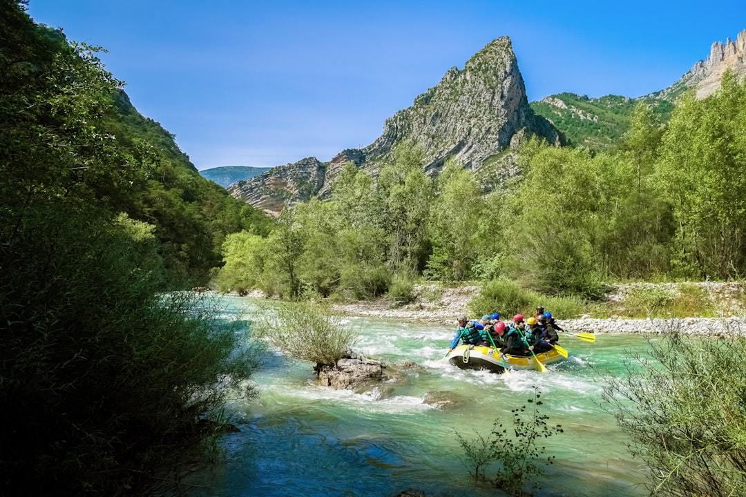 people riding on yellow kayak on river near green trees and mountain during daytime