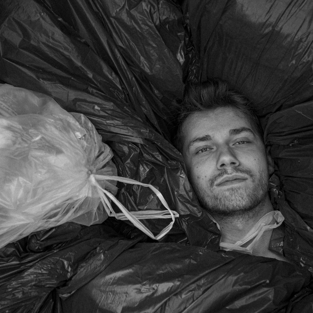 grayscale photo of man lying on bed