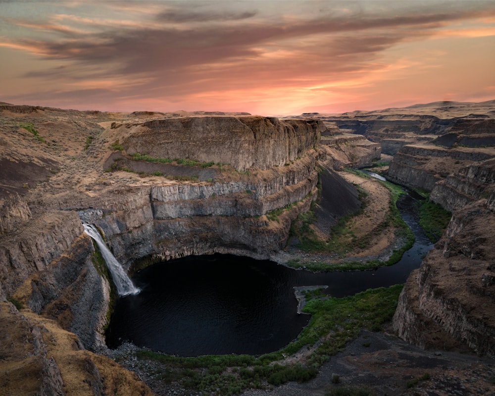 water falls on brown rocky mountain during sunset