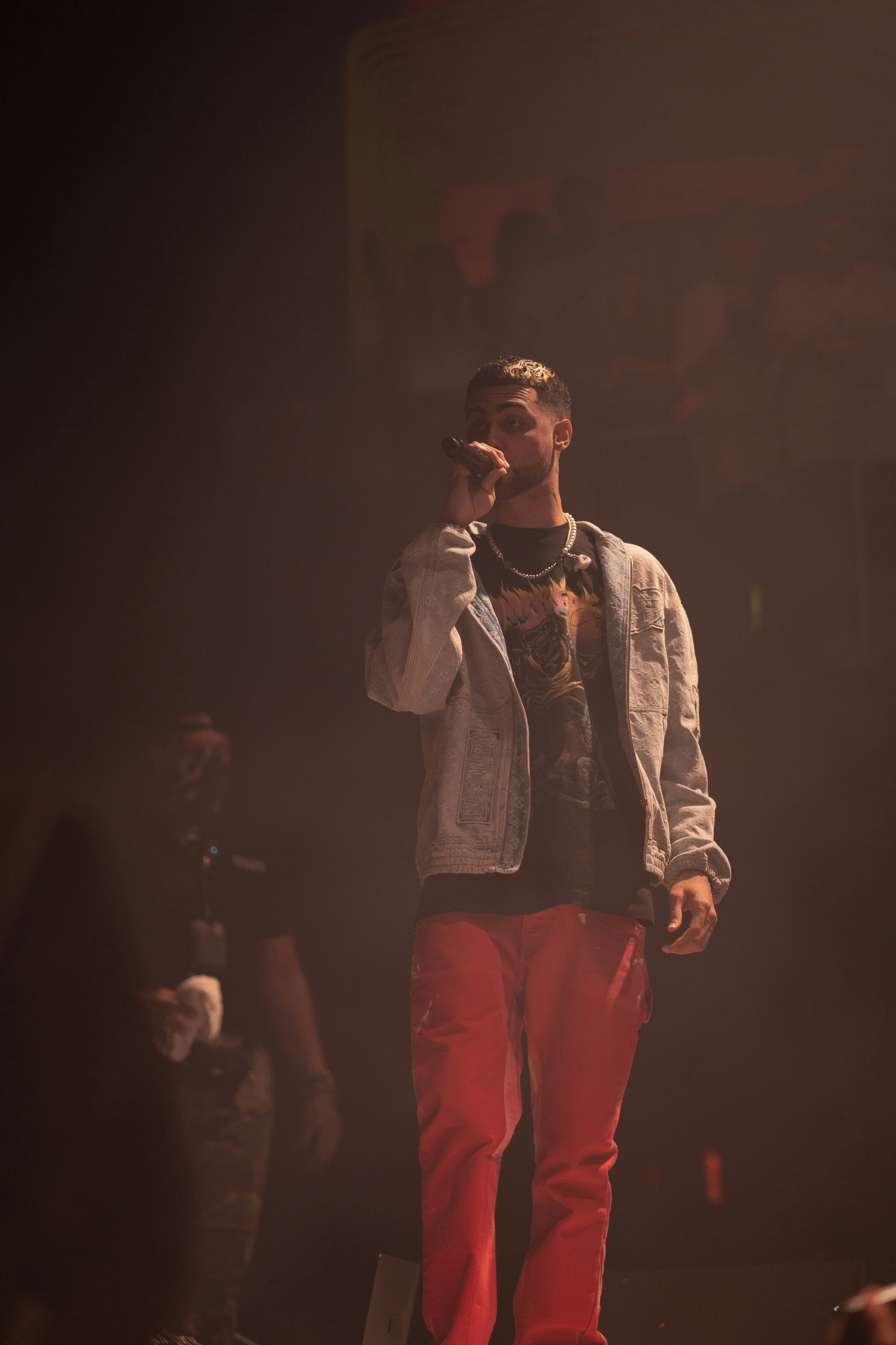 man in white dress shirt and red pants singing