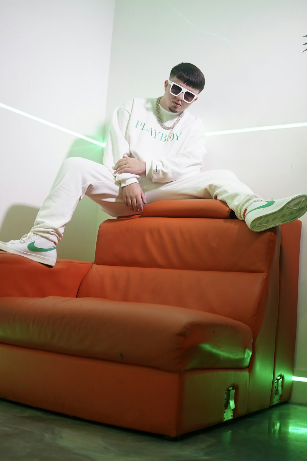 man in white long sleeve shirt and green pants sitting on brown leather couch