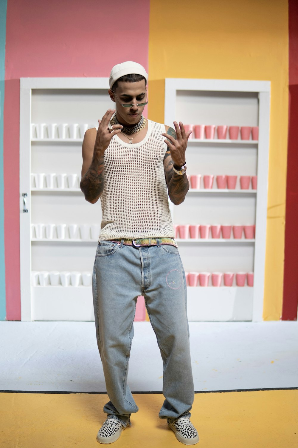 man in gray sweater and blue denim jeans standing on white floor