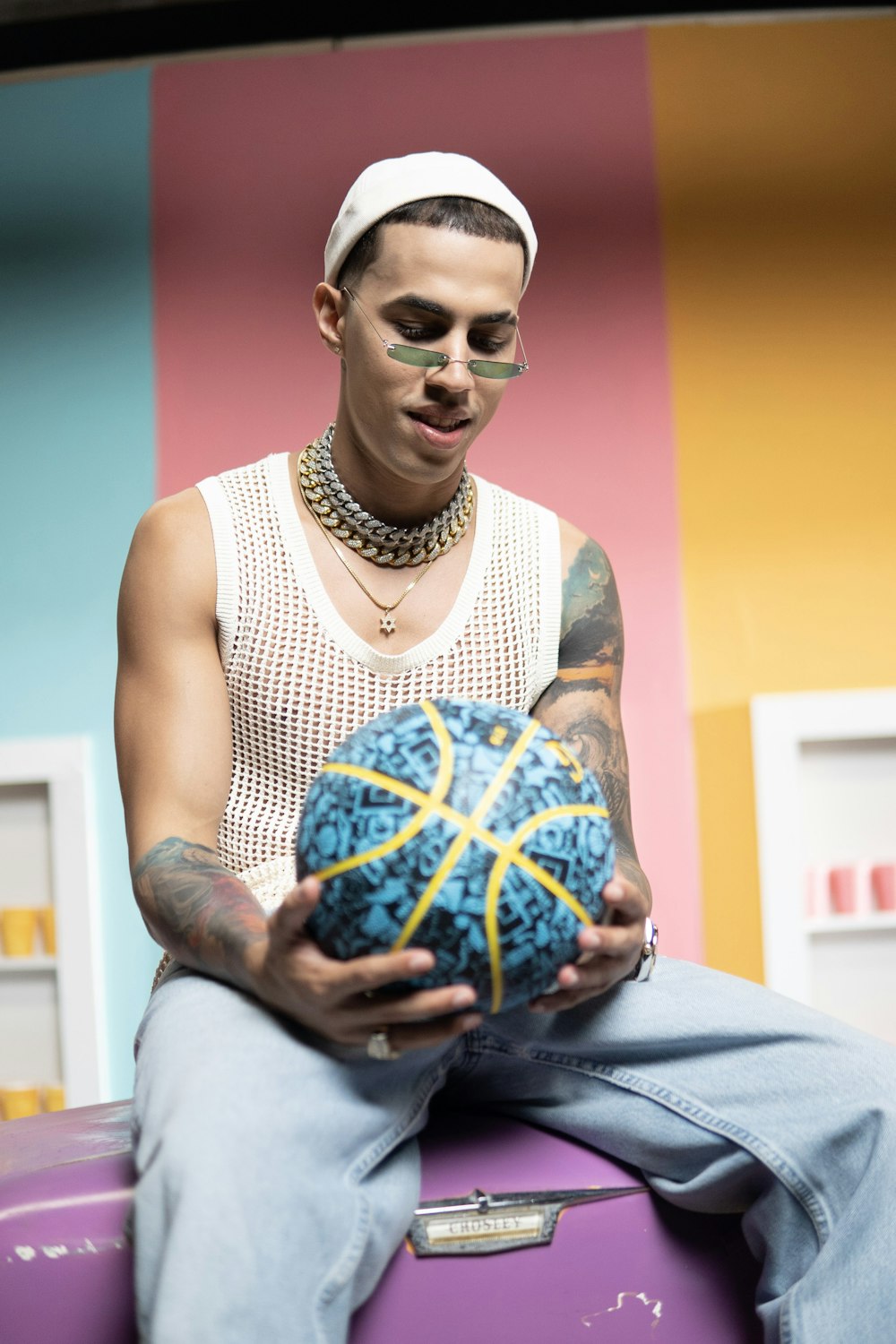 man in white tank top holding blue and yellow ball