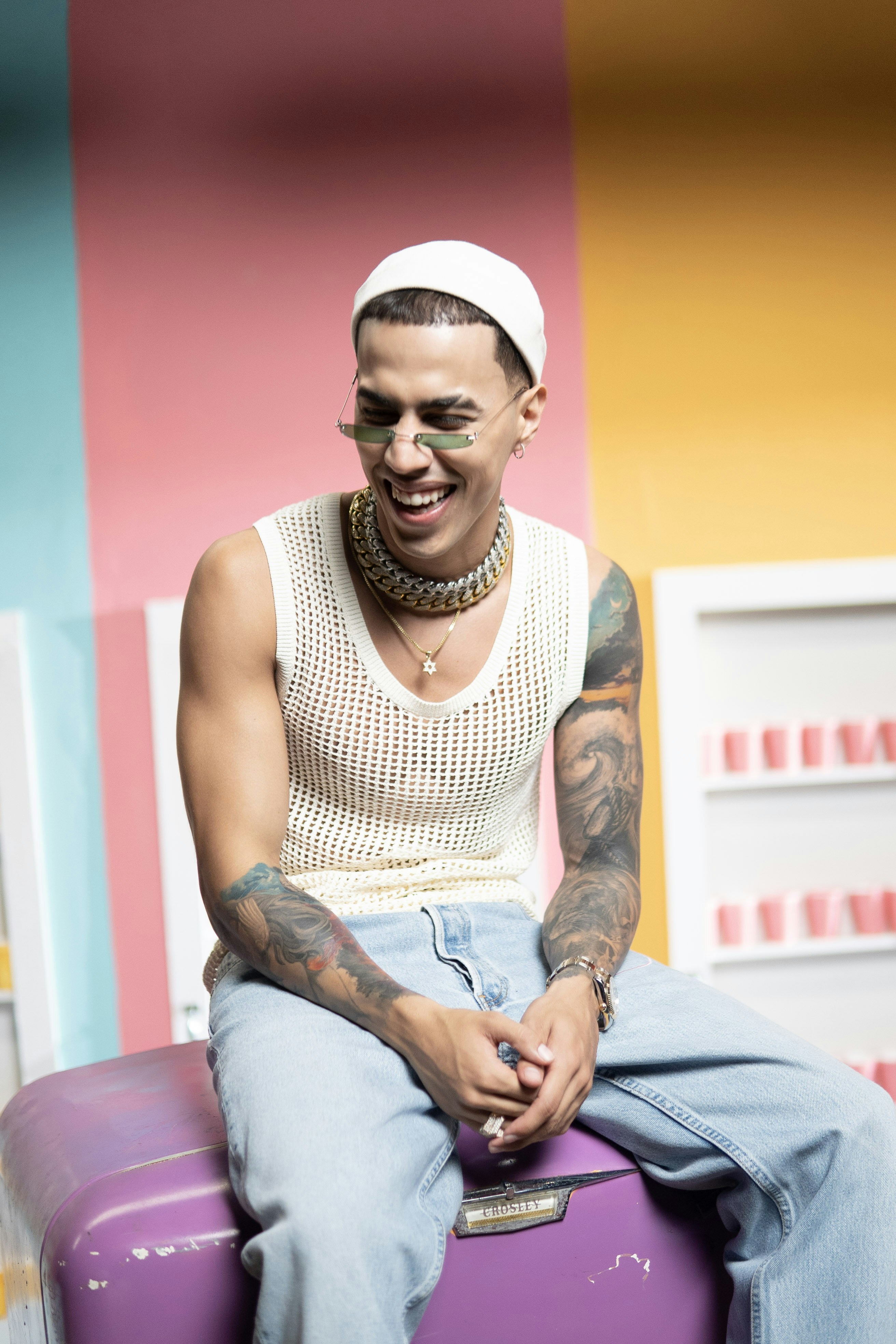 man in white tank top and blue denim jeans sitting on bed