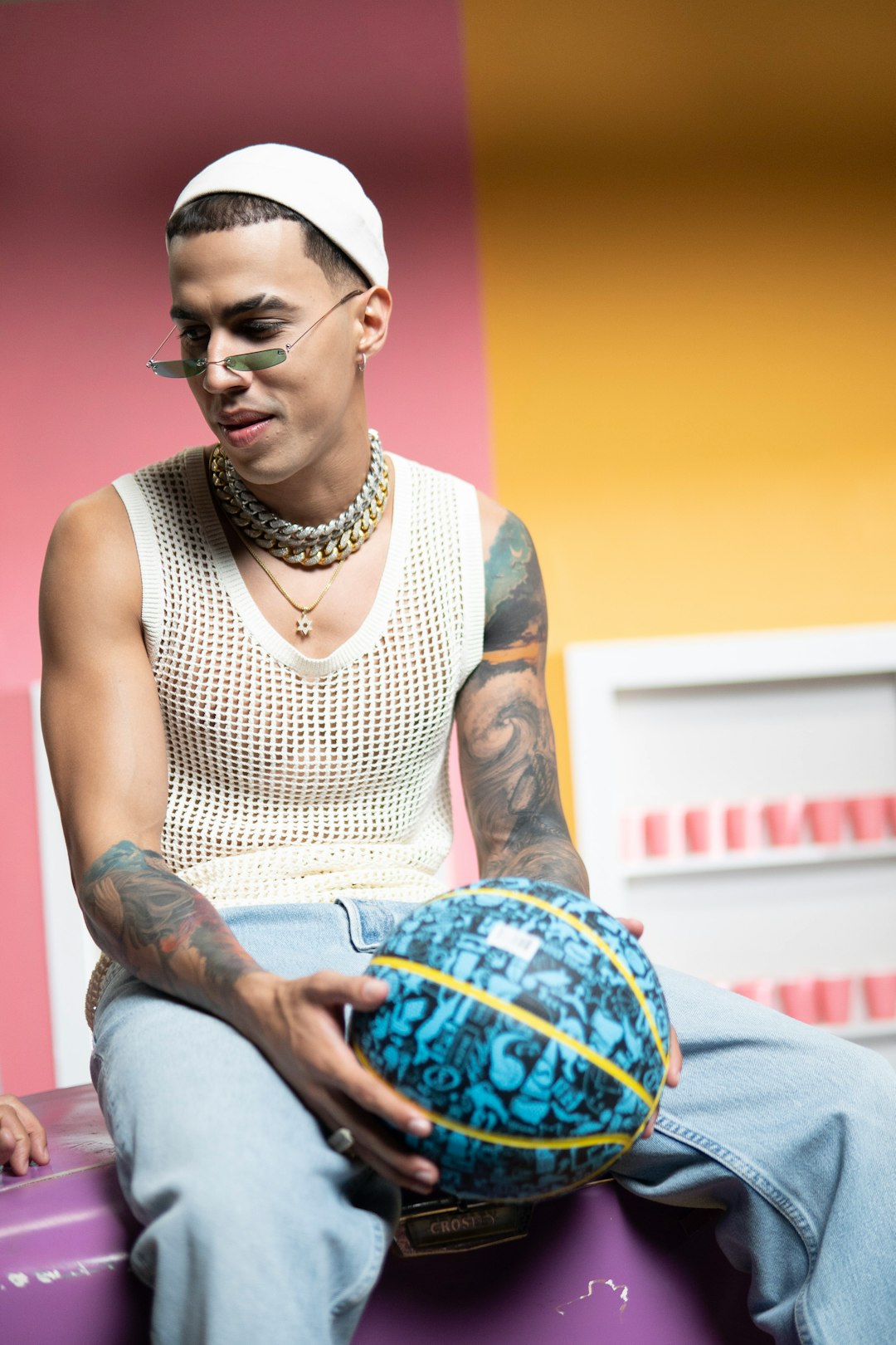 man in white tank top and blue denim jeans sitting on blue and white textile