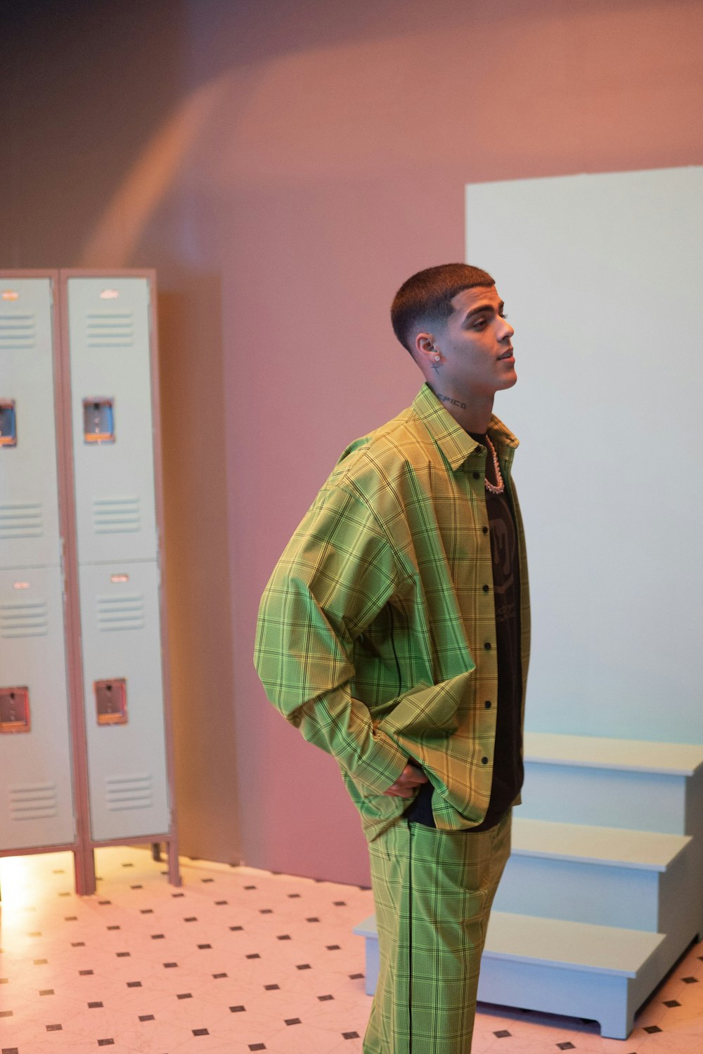 man in green and yellow plaid dress shirt standing near white cabinet