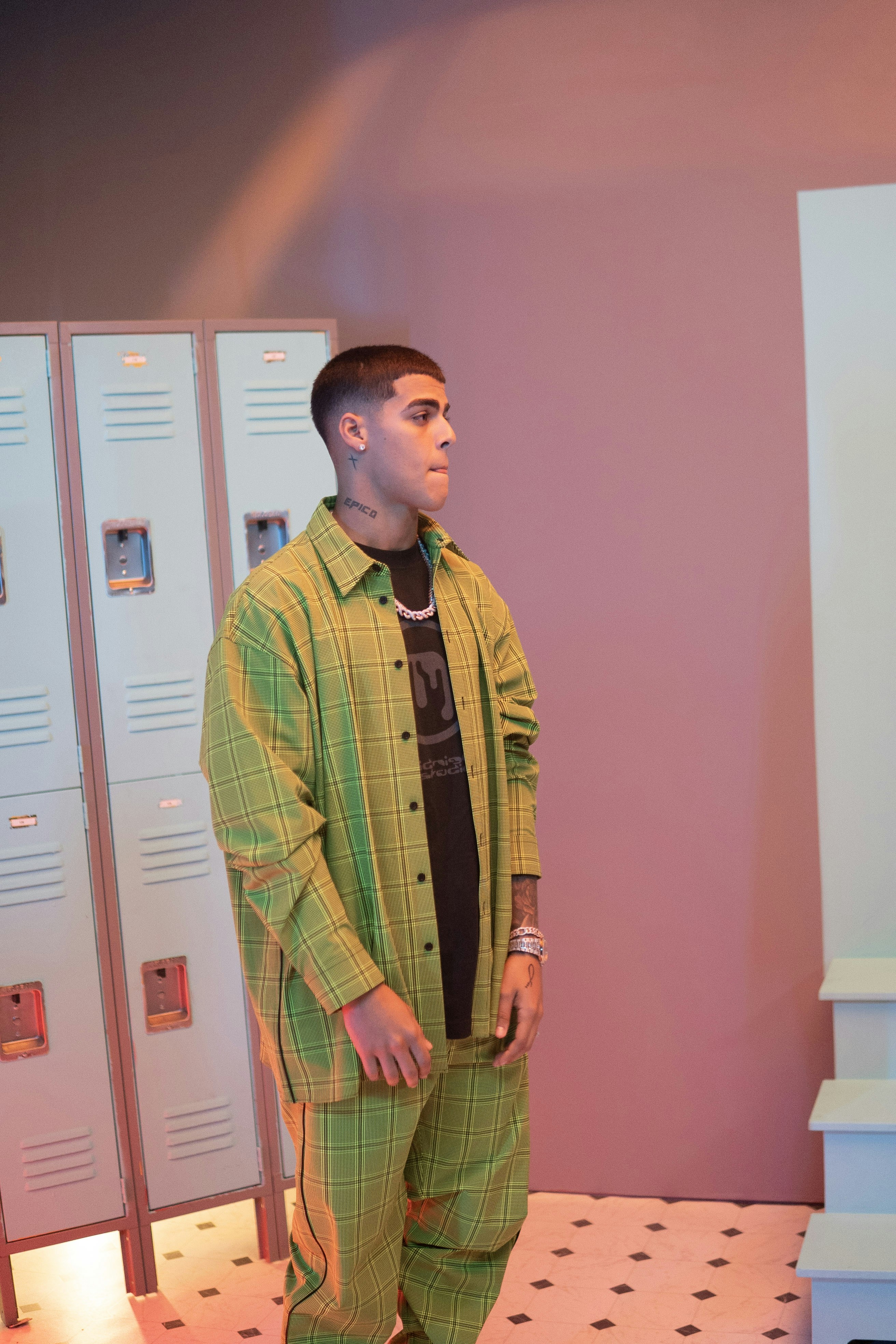 man in brown and white plaid button up long sleeve shirt standing beside pink wall