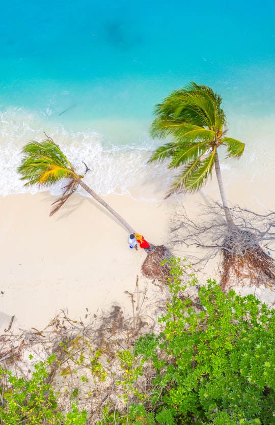 person in red shirt standing on white sand during daytime in Kurendhoo Maldives