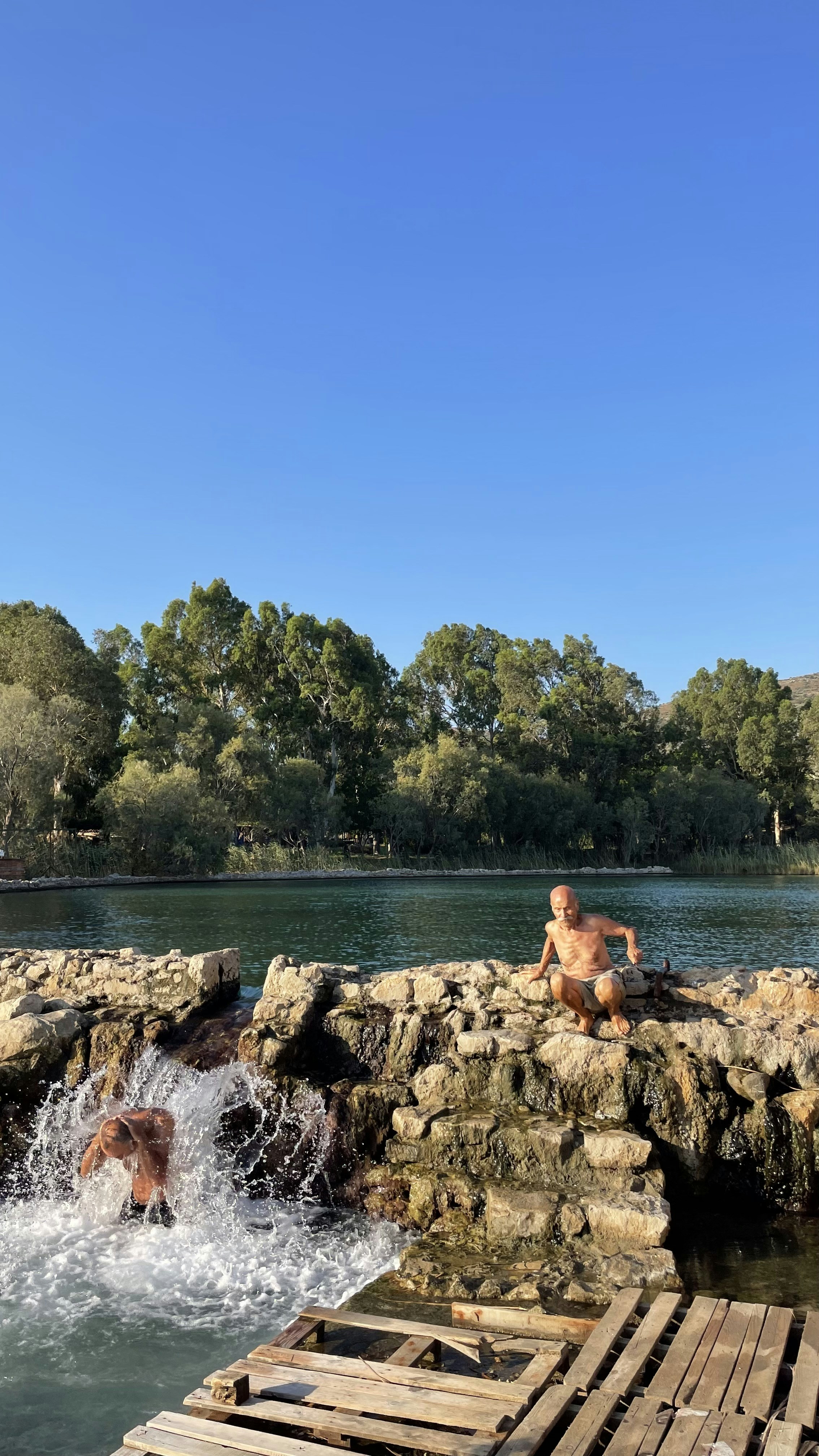 woman in black bikini sitting on rock near body of water during daytime