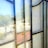 A reflection of a vintage car and a bright outdoor scene is visible through a stained glass window, with the window's pattern creating an overlay effect. The outside area features trees, a parked car, and a gravel pathway, with sunlight creating a blended, reflective appearance.
