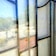 A reflection of a vintage car and a bright outdoor scene is visible through a stained glass window, with the window's pattern creating an overlay effect. The outside area features trees, a parked car, and a gravel pathway, with sunlight creating a blended, reflective appearance.