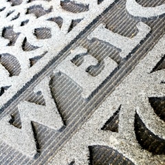 Close-up of a custom company logo mat placed at an office entrance.