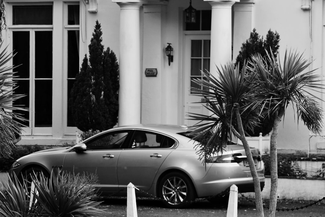 grayscale photo of coupe parked near building