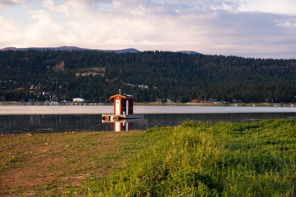 Casa di legno marrone sul campo di erba verde vicino allo specchio d'acqua durante il giorno