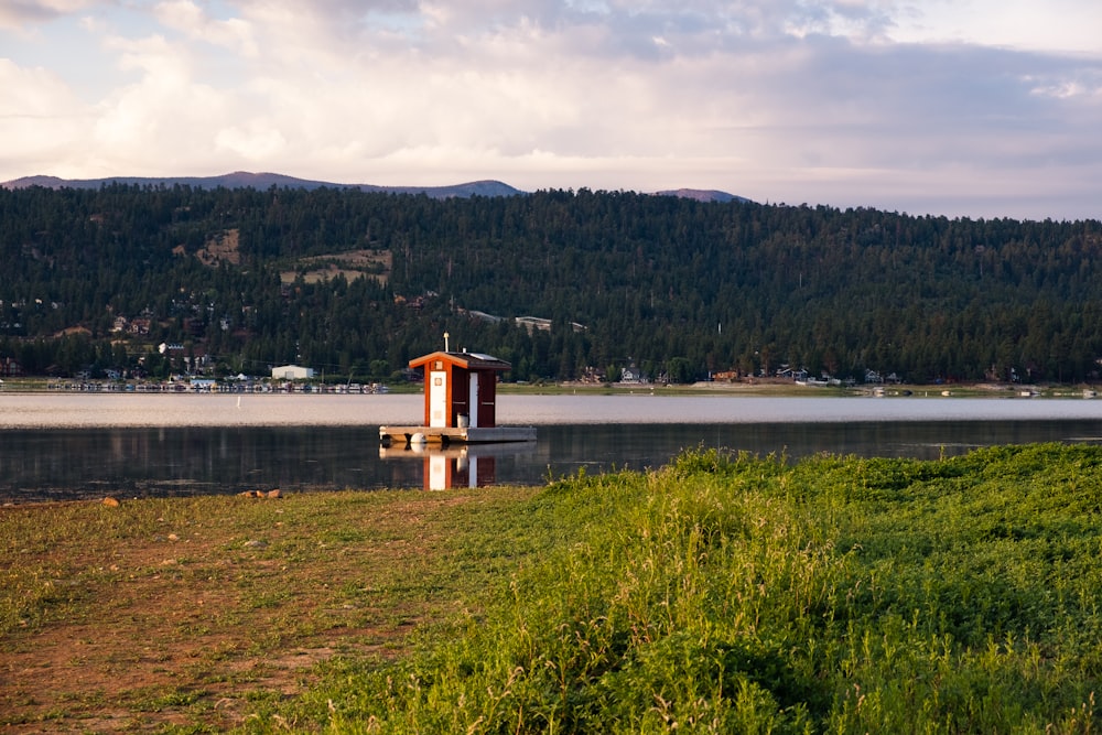 braunes Holzhaus auf grünem Rasenfeld in der Nähe von Gewässern tagsüber