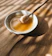 Smiling woman enjoying a spoonful of golden honey in a bright kitchen.