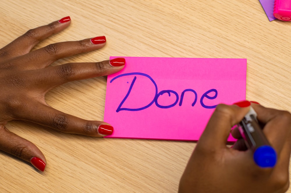 person with red manicure holding purple paper