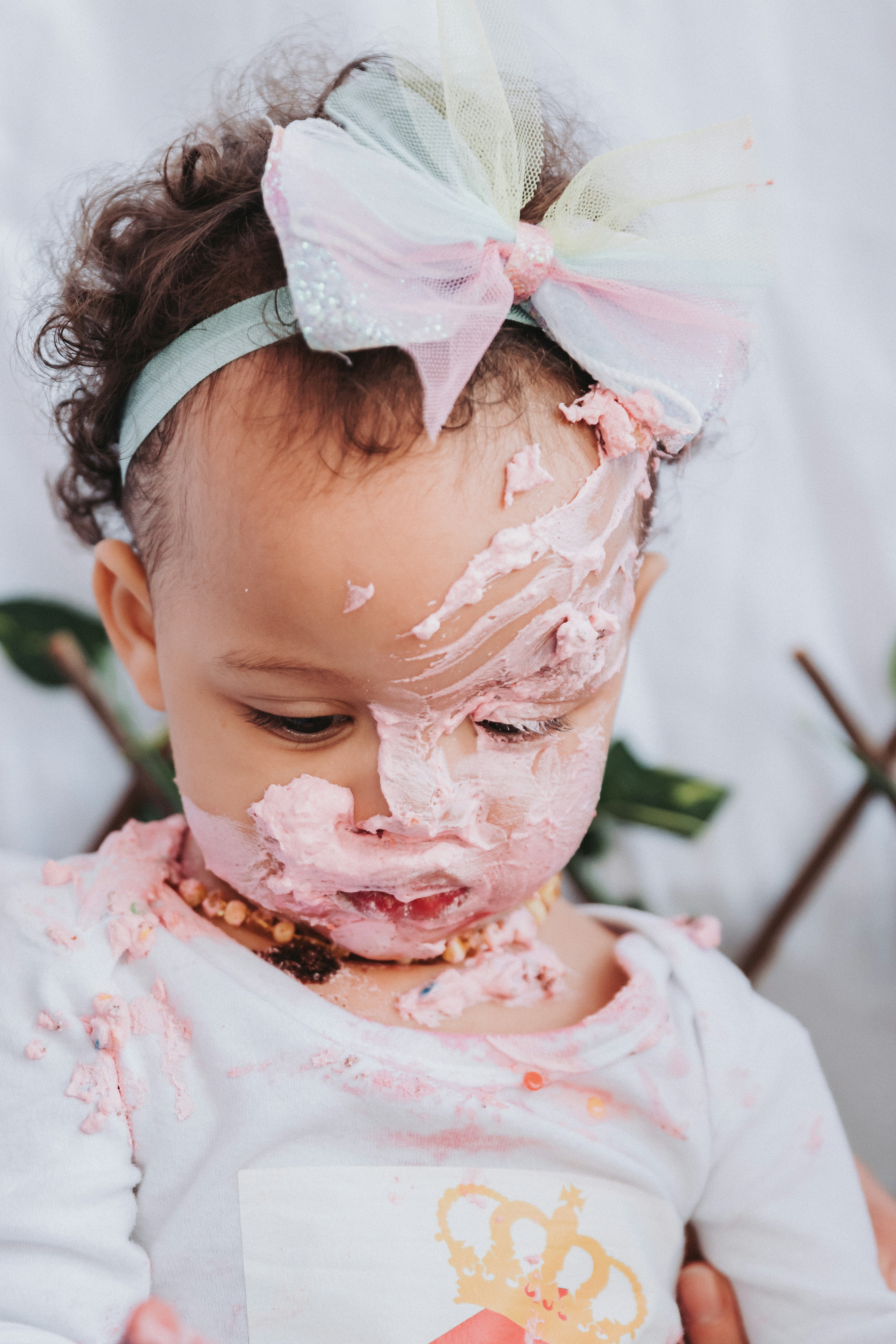 girl in white and pink floral shirt with white cream on face