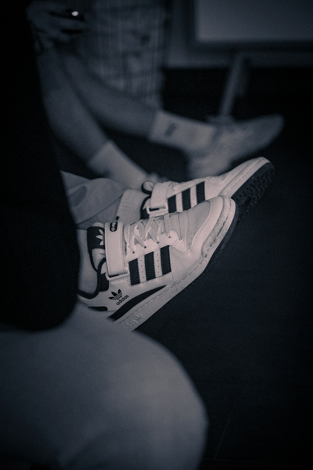 person wearing black and white adidas low top sneakers