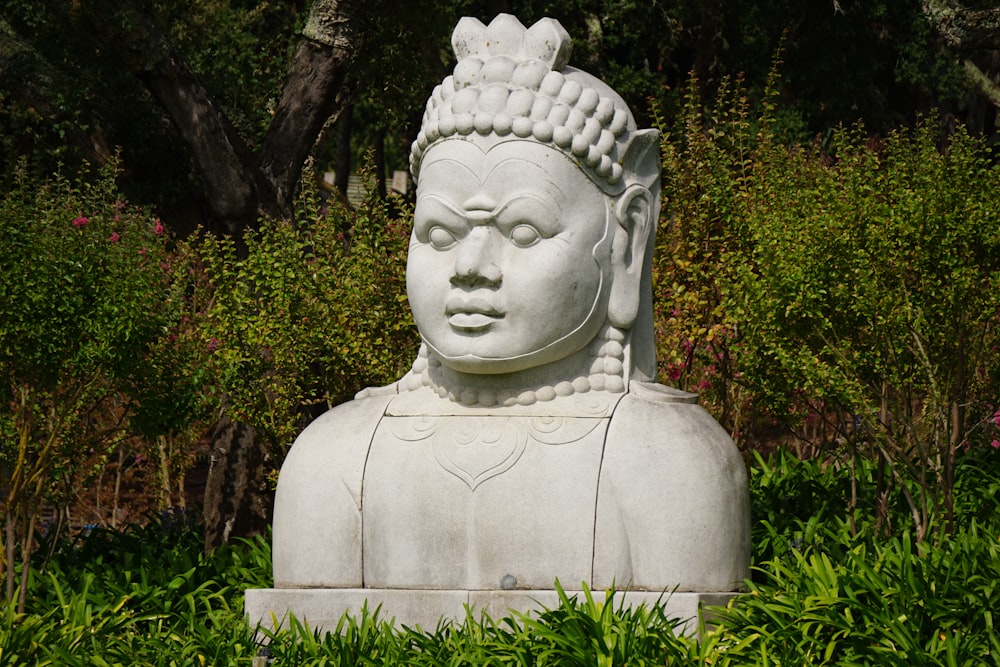 white concrete statue near green plants during daytime