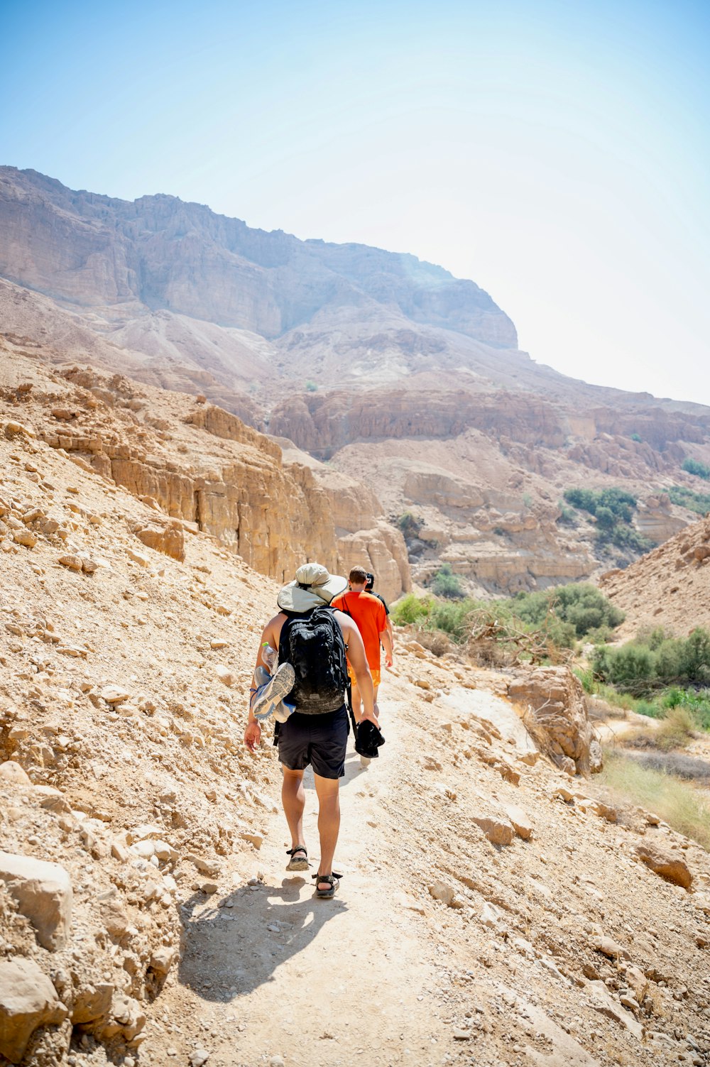 man in white shirt and black shorts walking on brown rocky mountain during daytime