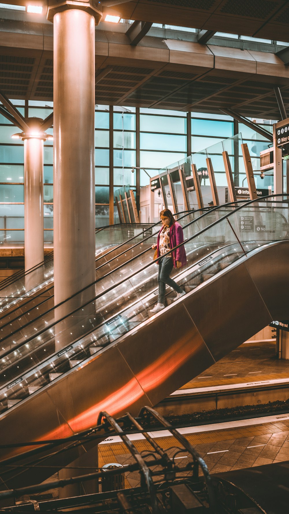 woman in red jacket standing on escalator