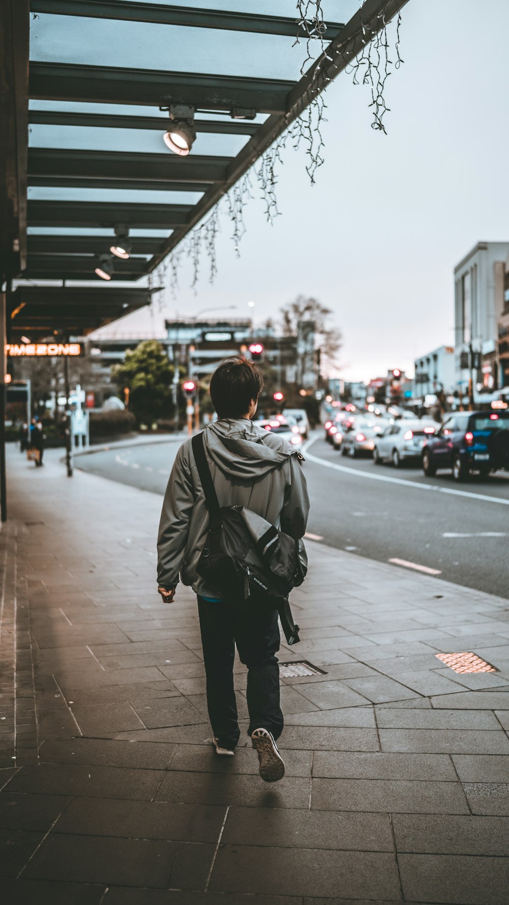 man in black jacket and black pants walking on sidewalk during daytime