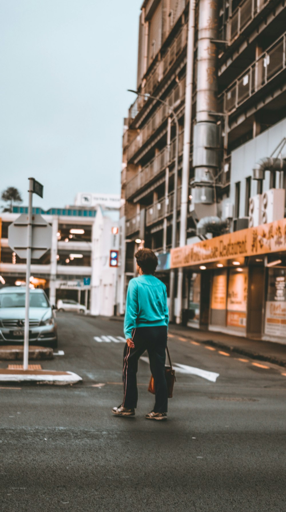 man in blue long sleeve shirt and black pants walking on sidewalk during daytime