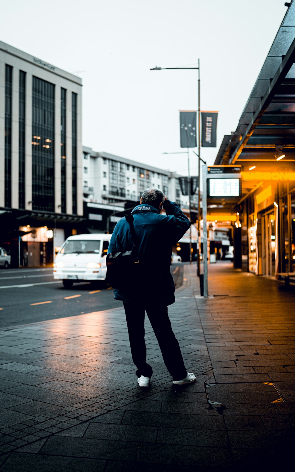 man in black jacket and black pants walking on sidewalk during daytime