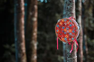 A rustic tambourine decorated with traditional Peruvian motifs against a backdrop of mountain scenery.